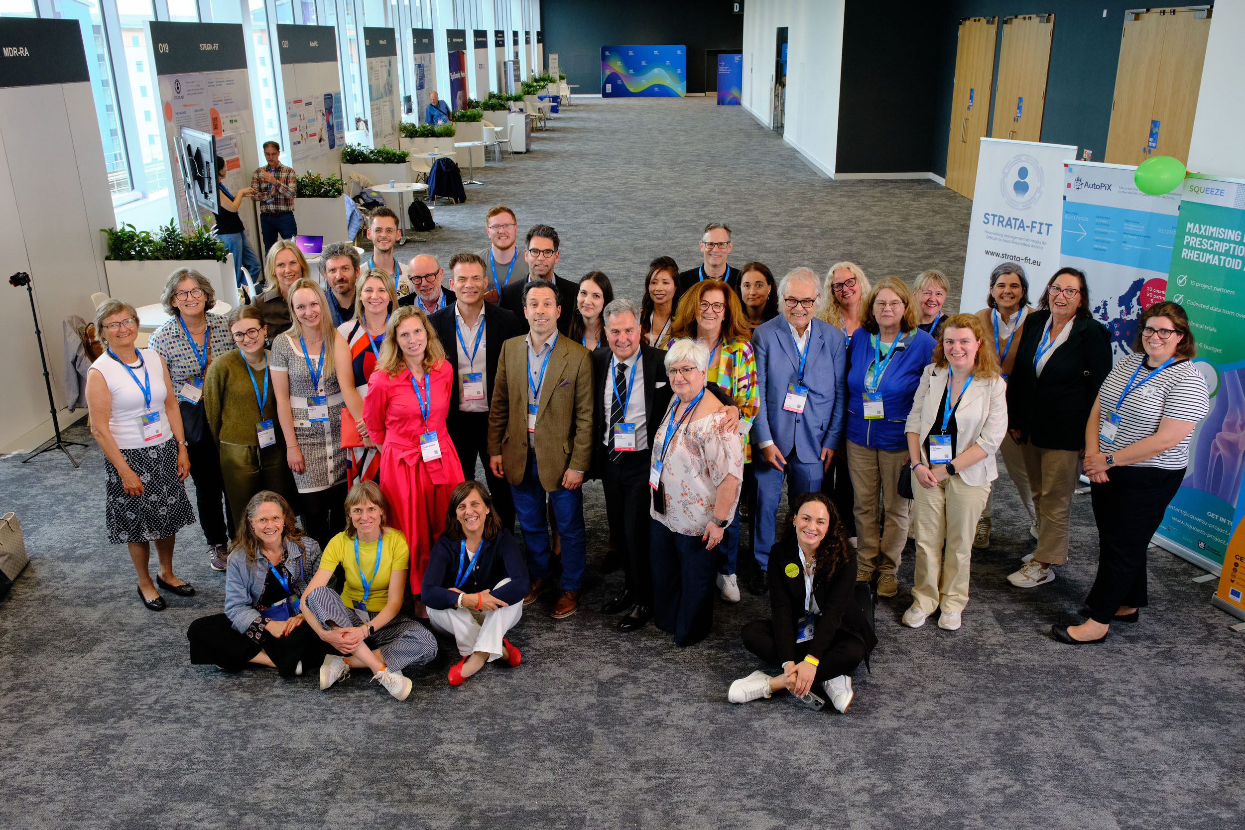 A group of people, smiling into the camera. In the background a conference setting