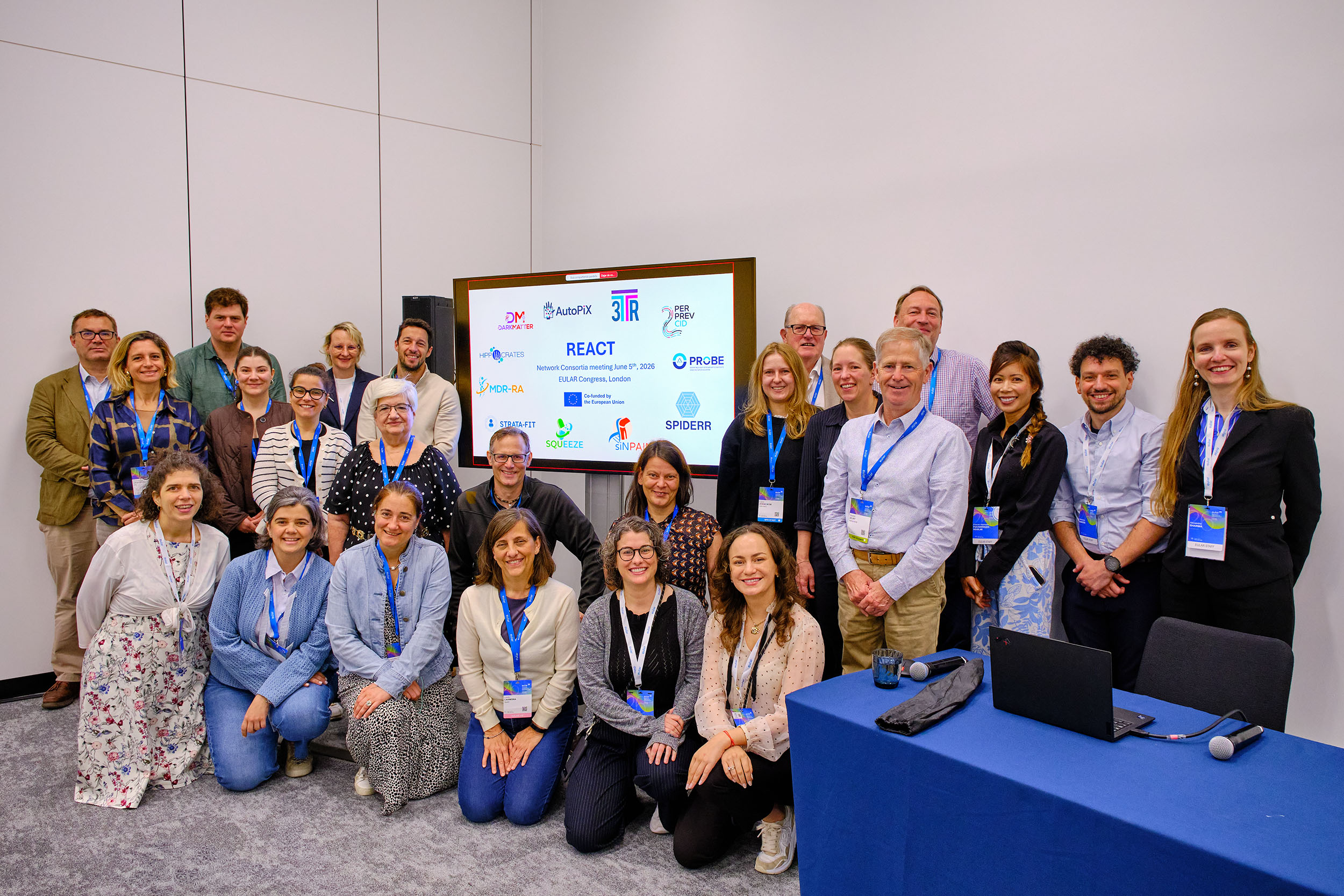 EULAR26_day3_0017 A group of people posing for the camera around a screen with project logos